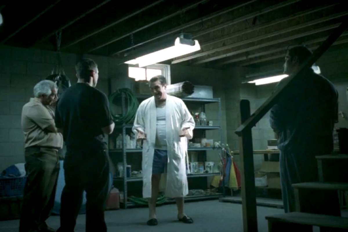 a mob boss in a bathrobe meets with his guys in a basement